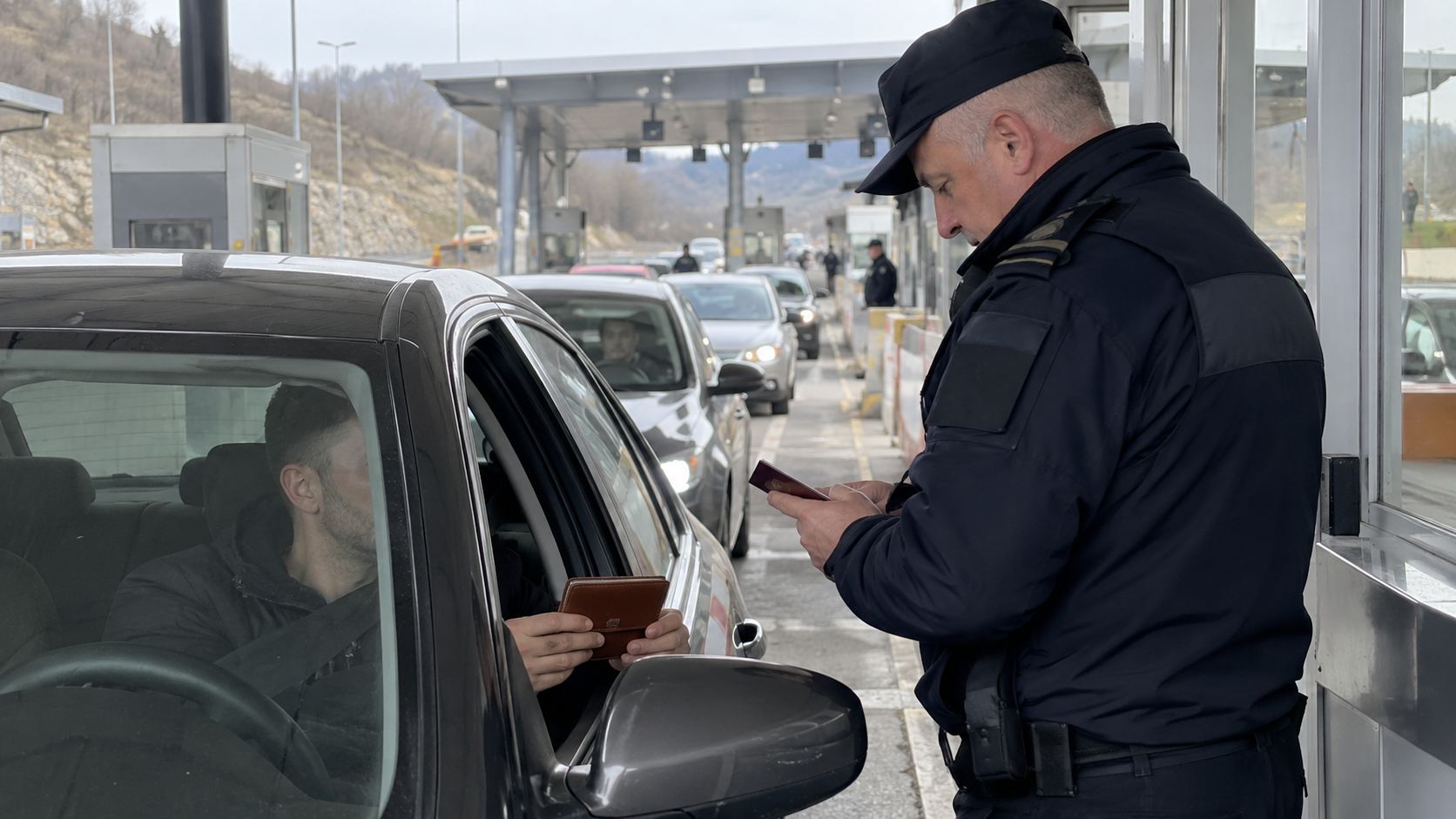 Vozač pokazuje novčanik dok carinik proverava dokumenta na granici